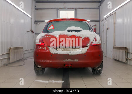 Russland Kemerovo 2019-01-05 Zurück von Suzuki Swift hellen roten Kleinwagen im Schmutz Schnee auf professionelle Fahrzeugreinigung. Konzept die umfassende Pflege für Außen, ich Stockfoto