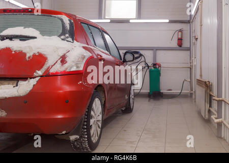 Russland Kemerovo 2019-01-05 Zurück von Suzuki Swift hellen roten Kleinwagen im Schmutz Schnee auf professionelle Fahrzeugreinigung. Konzept die umfassende Pflege für Außen, ich Stockfoto