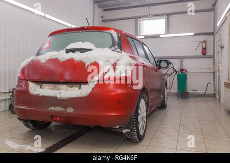 Russland Kemerovo 2019-01-05 Zurück von Suzuki Swift hellen roten Kleinwagen im Schmutz Schnee auf professionelle Fahrzeugreinigung. Konzept die umfassende Pflege für Außen, ich Stockfoto