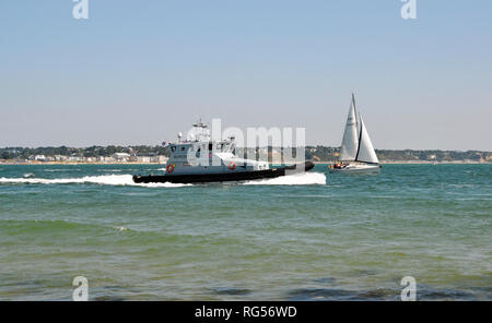 Grenze Patrouille und ein Segelboot bei Shell Bay, Swanage, Isle of Purbeck, Dorset, England, UK. Blick vom Strand. Stockfoto