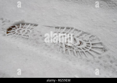 Spuren von Schuhen auf einem Schnee - gefüllte Straße. Impressum von einem Schuh im Schnee. Jahreszeit Winter. Stockfoto