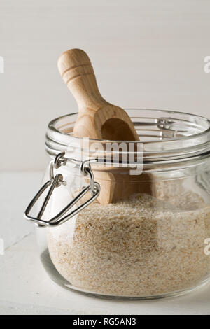 Haufen psyllium husk auch genannt Isabgol in Glas Glas mit Holz- Schaufel auf weißem Hintergrund. Psyllium husk auch genannt Isabgol ist Faser abgeleitet Stockfoto