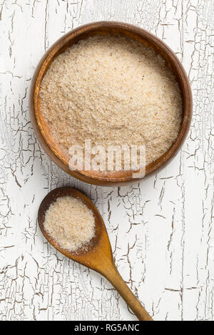 Haufen psyllium husk auch genannt Isabgol in hölzerne Schüssel und Löffel auf weißem Hintergrund. Psyllium husk auch genannt Isabgol ist Faser abgeleitet von Stockfoto