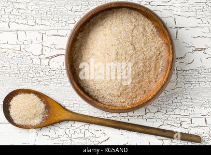 Haufen psyllium husk auch genannt Isabgol in hölzerne Schüssel und Löffel auf weißem Hintergrund. Psyllium husk auch genannt Isabgol ist Faser abgeleitet von Stockfoto