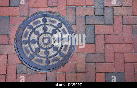 Nahaufnahme Foto eines Sturmabwasserkanal Kanaldeckel auf einem Stein Bürgersteig. Stockfoto