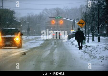 Bartlett, Illinois, USA. Ein schneesturm Auswirkungen Hauptstraße in der Region Chicago als Mann zu waling in der Straße bei der Vermeidung von Schnee verpackt Bürgersteige. Stockfoto