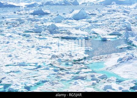 Ilulissat, Grönland, Juli | UNESCO-Weltkulturerbe | Diskobucht Kangia Icefjord | riesige Eisberge im blauen Meer an einem sonnigen Tag - globale Erwärmung Stockfoto