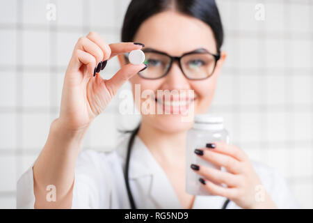 Junge Frau Doktor Holding und zeigt eine weiße natürliche Pille Stockfoto