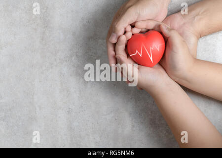 Vater und Kind Hände halten roten Herzen auf Marmor Hintergrund, Gesundheit, Liebe, Hoffnung und Familie Konzept, World Heart Day Stockfoto