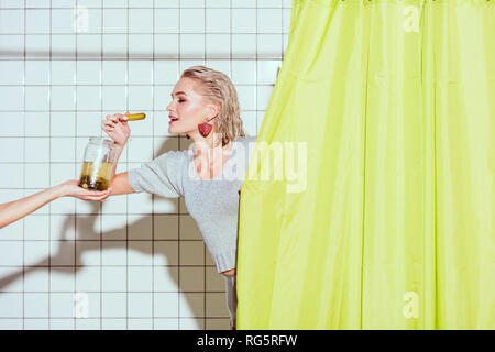 Schöne stilvolle Frau, die Gurken aus dem Glas Glas in der Dusche Stockfoto