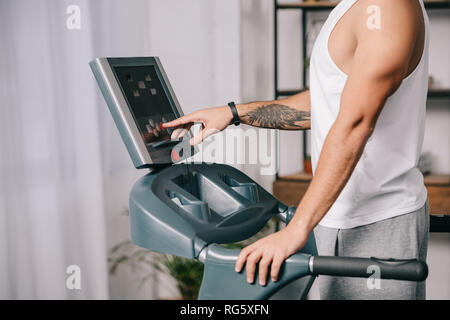 7/8-Ansicht der Sportler durch Drücken der Taste auf dem Bedienfeld des Laufband Stockfoto