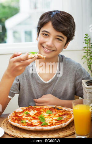 Portrait Of Happy Teen Boy mit Genuss essen Pizza, fröhlichen Teenager genießen Sie leckeres Essen und verbrachten ein tolles Wochenende zu Hause Stockfoto