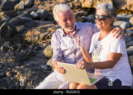 Gerne Lachen und Lächeln kaukasischen fröhlichen erwachsenen Reifes Paar Spaß im Freien mit Technologie Laptop zusammen unter der Sonne in vacati Stockfoto