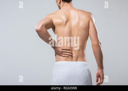 Ansicht der Rückseite des jungen Mannes leiden unter Rückenschmerzen, isoliert auf Grau Stockfoto