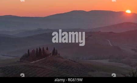 Die Sonne hinter den Hügeln der Val d'Orcia, Siena, Toskana, Italien Stockfoto
