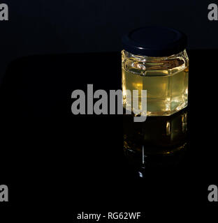 Trüffel Pilz in ein Glas Honig auf schwarzem Hintergrund. Minimalismus in der Komposition. Luxus essen. Freier Platz für Text Stockfoto