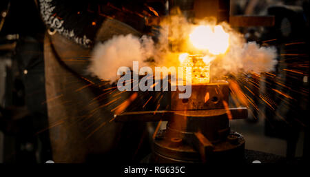 Schlosser schlägt das heiße Bügeleisen um die gewünschte Form zu geben. Stockfoto