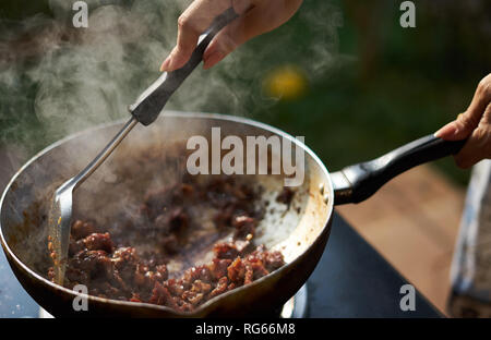 Frau Braten essen Rühren in Kochen pan Stockfoto