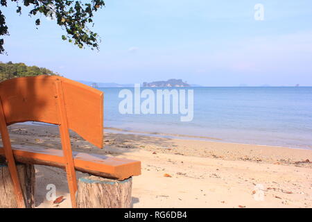 Holzbank am Strand einer thailändischen Insel mit Ausblick aufs Meer und die umgebenden Inseln Stockfoto
