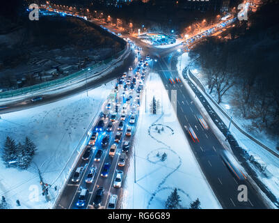 Luftaufnahme von Straßen in der Stadt in der Nacht im Winter. Blick von oben auf den Verkehr in der Straße mit Beleuchtung. Landschaft mit Autos, verschneite Straße in Europa. Ich besetzt Stockfoto