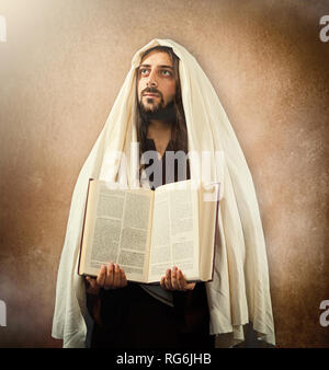 Jesus zeigt die Heilige Bibel auf alten beigen Hintergrund Stockfoto