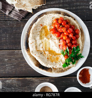 Kichererbse hummus serviert auf Fladenbrot mit Kirschtomaten, Ansicht von oben Stockfoto