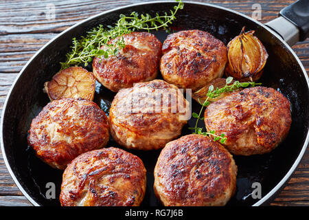 Saftig lecker gebratenen Truthahn, Huhn Frikadellen, Schnitzel von Hackfleisch in einer Pfanne mit Thymian, Knoblauch und Zwiebel auf einem alten Holztisch, Ansicht von Abo Stockfoto