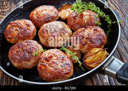 Gebratener Truthahn, Hähnchen, Burger, Schnitzel von Hackfleisch in einer Pfanne mit Thymian, Knoblauch und Zwiebel auf einem alten Holztisch, horizontal Ansicht von oben Stockfoto