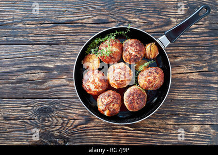 Saftige köstliche hausgemachte gebratener Truthahn, Hähnchen Schnitzel, Frikadellen aus gehacktem Fleisch in einer Pfanne mit Thymian, Knoblauch und Zwiebel auf einem alten Holztisch, Anzeigen Stockfoto