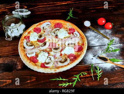 Italienische fast food. Köstliche heiße Pizza geschnitten und serviert auf Holz- platte mit Zutaten, die Ansicht zu schließen. Menü Foto Stockfoto