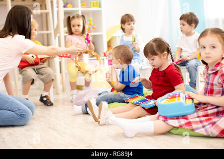 Lehrer und niedliche Kinder während der musikstunde im Kindergarten Stockfoto