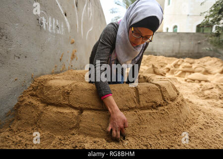 (190128) - GAZA, Jan. 28, 2019 (Xinhua) - Sand Artist Rana Ramlawi arbeitet auf ihrem Sand Skulpturen in Gaza Stadt, Jan. 24, 2019. Rana Ramlawi, ein 23 Jahre alter palästinensischer Junge Frau aus dem Gazastreifen, Erholungsorte auf Sand Kunst die Sache der Palästinenser und die israelisch-palästinensischen Konflikt zu markieren. In ihren Skulpturen aus Sand und Wasser hergestellt, viele Meldungen in Unterstützung der palästinensischen Sache vermittelt, da sie glaubt, dass Kunst ist ein wichtiger Weg, um die Rechte und die Forderung nach Freiheit zu betonen und die Beendigung der israelischen Besatzung. "Eines meiner Ziele in meinen Arbeiten ist dieses Erbe zu bewahren und zu sagen Stockfoto