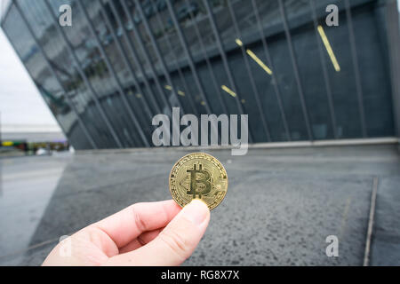 Bitcoin Goldmünze, Hand halten Bitcoin infront der Business Architektur Stockfoto