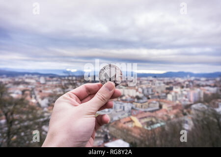 Monero Silbermünze, Hand halten Monero oben über der Stadt Stockfoto