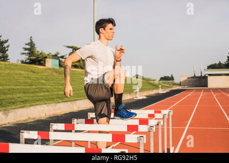 Athlet, Warm-up Übungen auf einer tartanbahn Für eine Hurdle Race Stockfoto