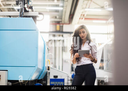 Frau mit Tablette Maschine im Factory Shop Boden Stockfoto