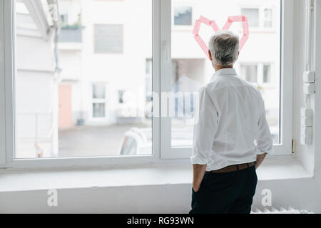Unternehmer durch ein Fenster mit einem Herz-Form, Rückansicht Stockfoto