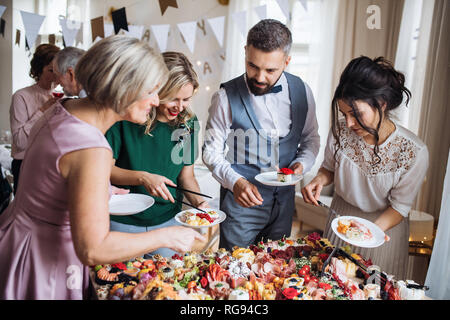 Eine multigeneration Familie das Essen auf den Tellern auf einer Innen- Geburtstagsfeier in der Familie. Stockfoto