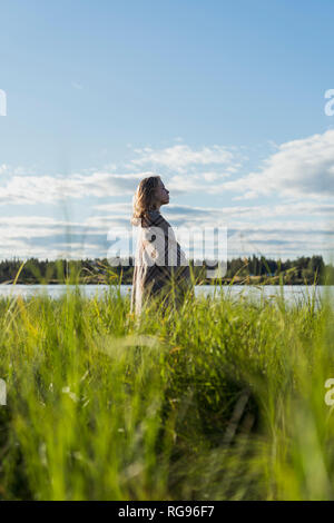 Finnland, Lappland, Frau in eine Decke eingewickelt an der Lakeside Stockfoto