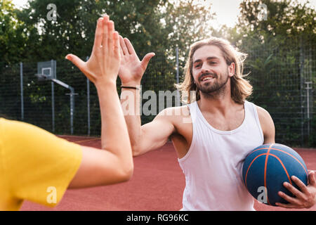 Junger Mann und eine junge Frau, high-fiving nach Basketball Spiel Stockfoto