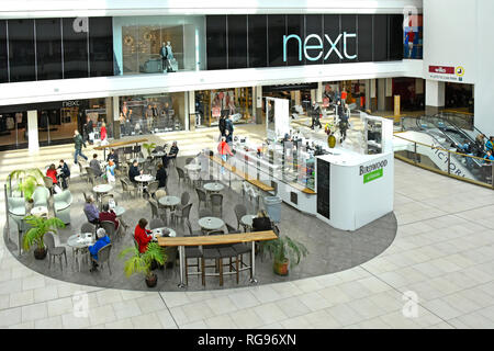 Suchen von oben nach unten die Menschen am inneren cafe Tabellen nächste Bekleidungsgeschäft Rolltreppe über Shopper in Shopping Center Mall Southend Essex UK sitzen Stockfoto