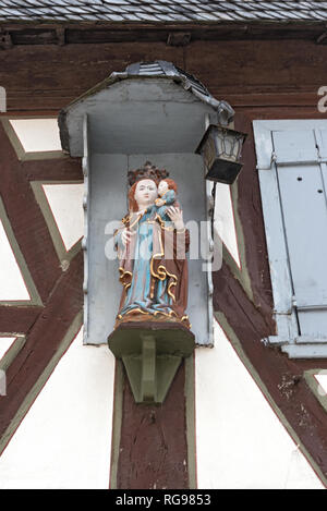 Die Statue der Jungfrau Maria und Jesus Jungen an der Außenwand eines alten Fachwerkhauses Stockfoto