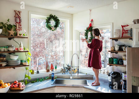 Mädchen stehen auf einer Küchenarbeitsplatte herauf Weihnachtsdekorationen Stockfoto