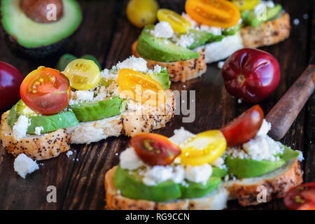 Avocado toast Sandwich mit avocadeos, frisch aus dem Garten heirloom Tomaten und Feta Käse, griechisches Essen und gesunde vegetarische Ernährung Konzept, über einen Stockfoto