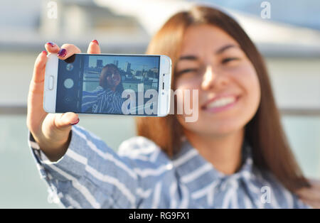 Ein Mädchen Schüler von asiatischen Aussehen lächelt schön und macht einen selfie, während auf der Straße Stockfoto