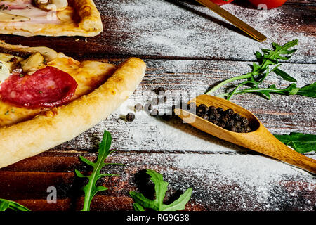 Italienische fast food. Köstliche heiße Pizza geschnitten und serviert auf Holz- platte mit Zutaten, die Ansicht zu schließen. Menü Foto. Stockfoto