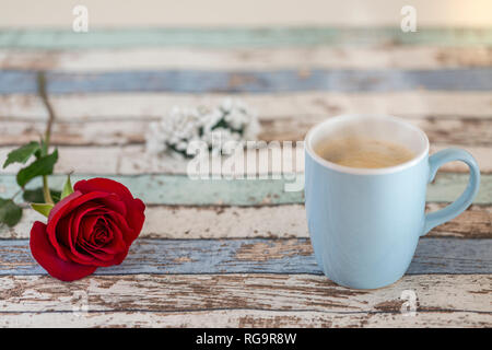 Kaffee in türkis Becher mit einer roten Rose und Blumen auf hölzernen Tisch Stockfoto