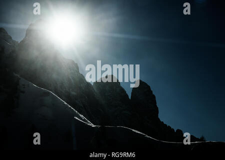 Silhouetted Schnee Berge Hänge und Gipfel mit Sonnenstrahlen und Flares. Corvara in Badia in den Dolomiten, Südtirol, Italien Stockfoto