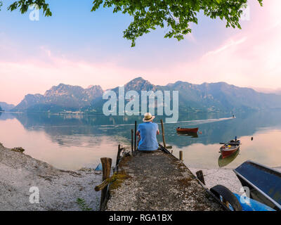 Italien, Lombardei, Rückansicht der Mann sitzt auf Mole in Idrosee bei Morgendämmerung Stockfoto