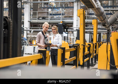 Zwei Frauen mit Tablet sprechen in Factory Shop Boden Stockfoto